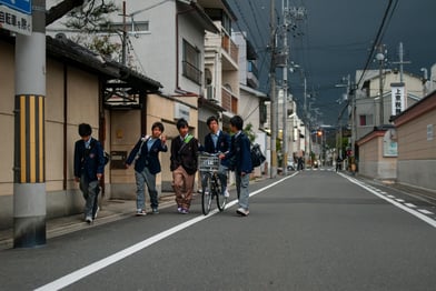 Skolpojkar i Japan promenerar längs en gata