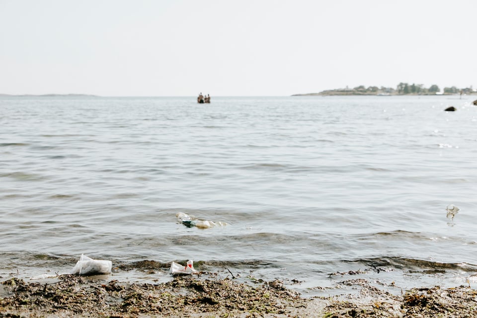 Strandkant med skräp i vattnet