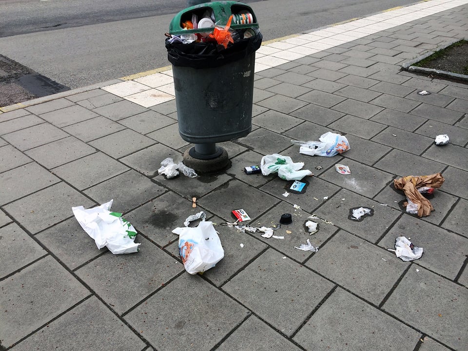 Överfull papperskorg i stadsmiljö