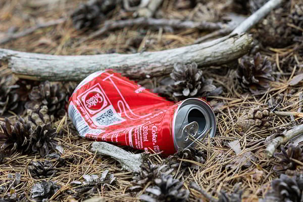 coca cola-burk slängt på marken i naturen